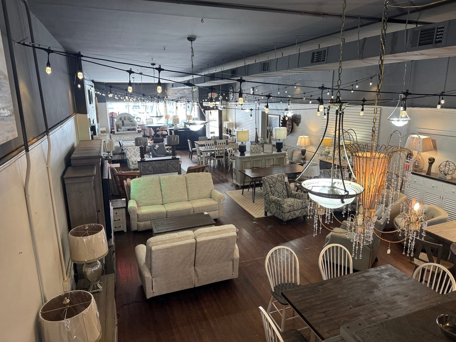 Warmly lit showroom with sofas, dining sets and chandeliers at Seneca Furniture Showcase